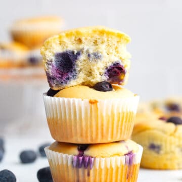 Keto blueberry muffins in a stack with the top one broken open.