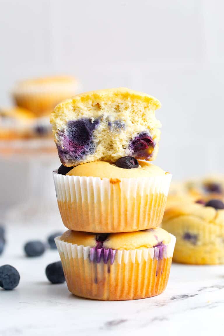 Keto blueberry muffins in a stack with the top one broken open.