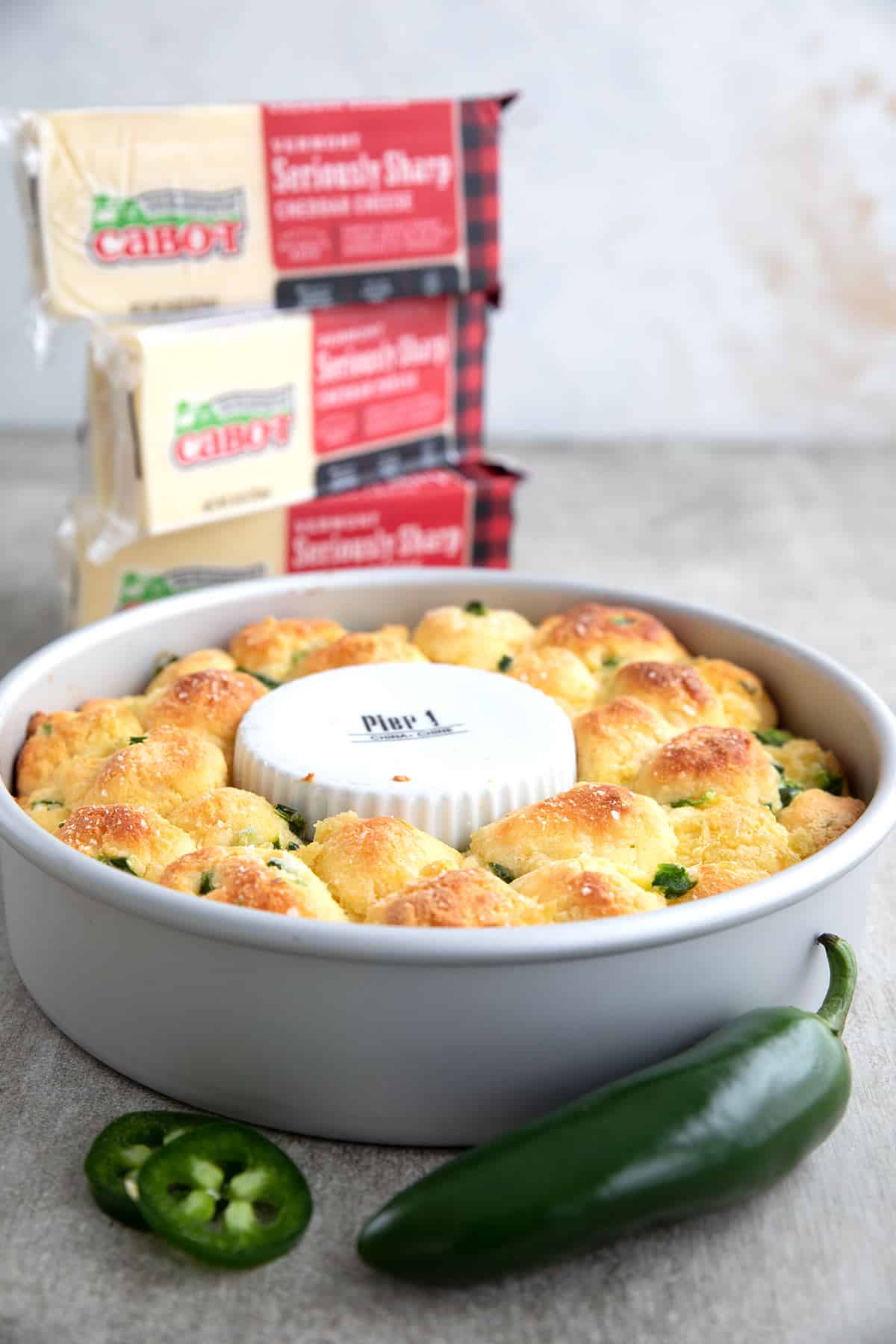 Keto Cheesy Monkey Bread in the pan with blocks of cheddar in the background.