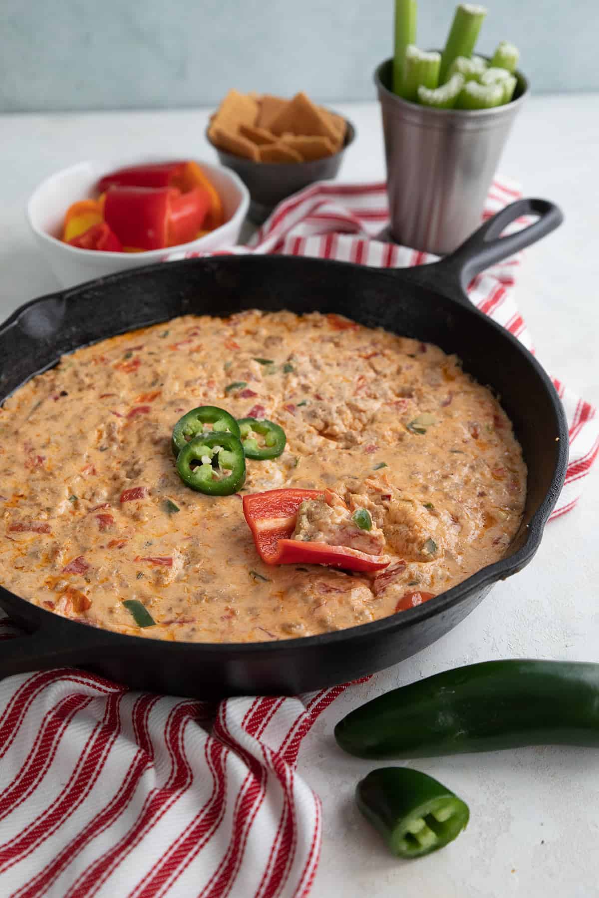 Sausage Dip in a skillet over a white and red striped napkin.