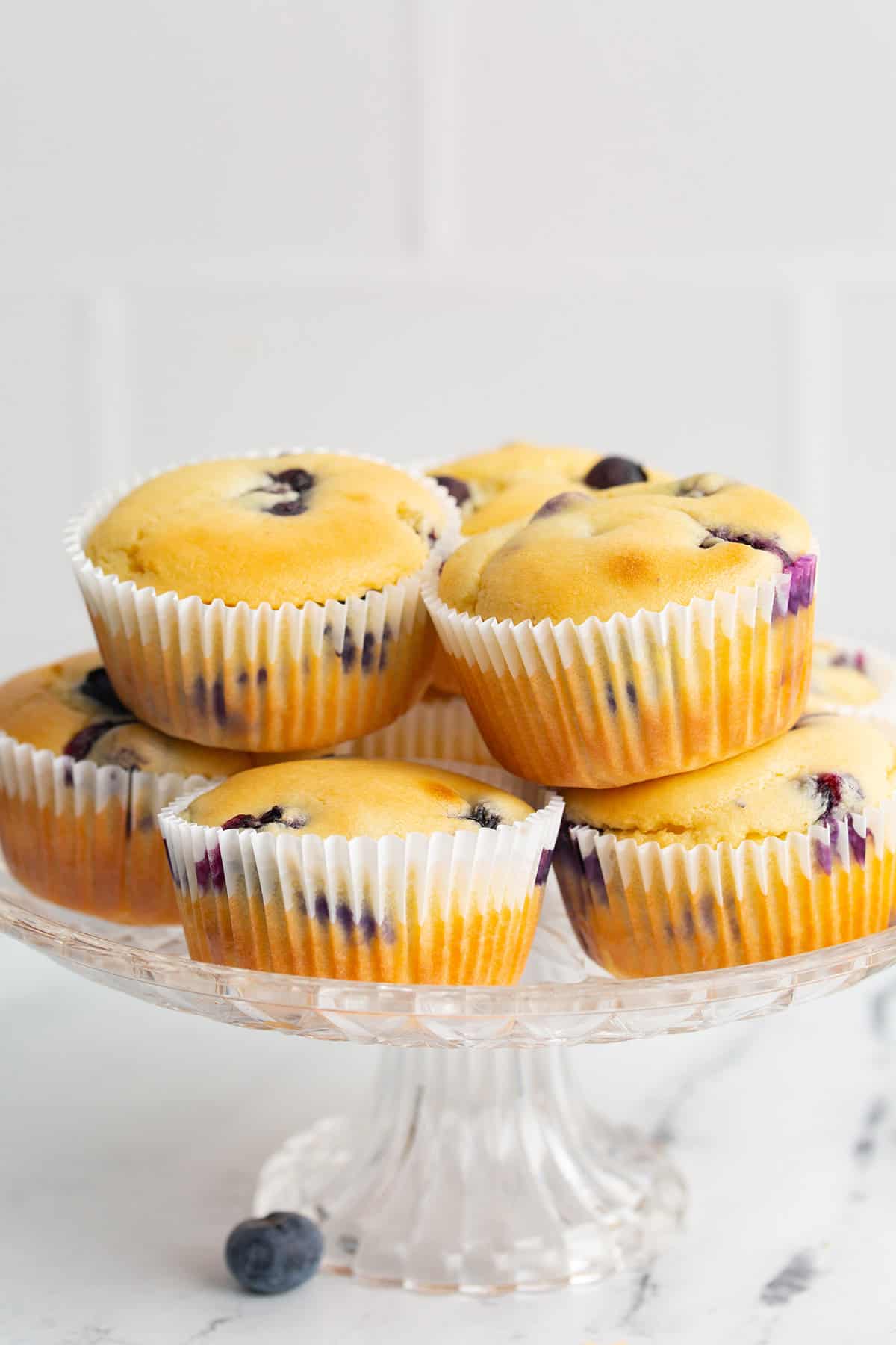 Keto Blueberry Muffins arranged on a glass cake stand.