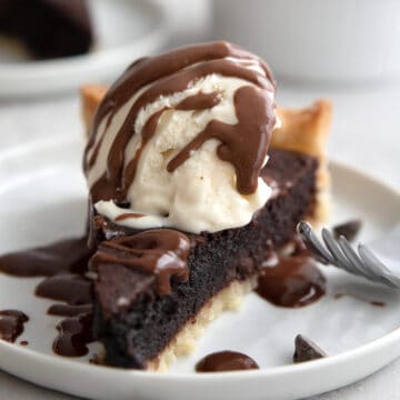 Close up shot of a slice of brownie pie with ice cream on top.