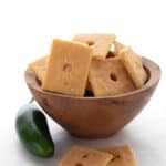 A wooden bowl filled with keto cheese crackers, with two in front.