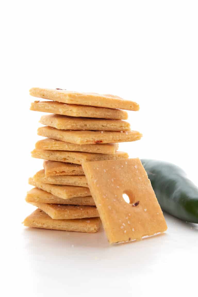 A stack of Keto Cheese Crackers on a white background with a jalapeno.