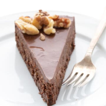 A slice of rich chocolate walnut torte on a white plate with a fork.