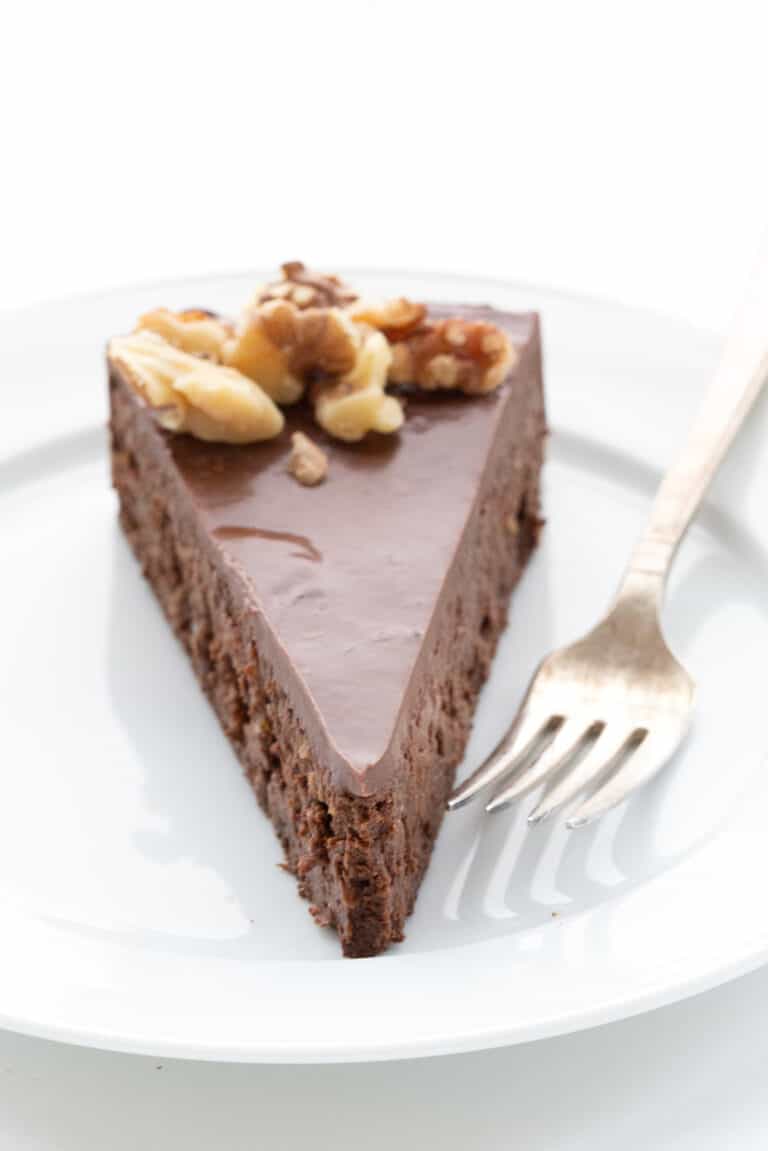 A slice of rich chocolate walnut torte on a white plate with a fork.