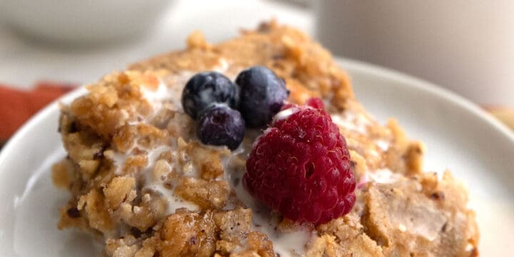 A serving of baked keto oatmeal on a white plate with berries on top.