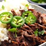 Close up image of Mexican shredded beef in a bowl with cauliflower rice and jalapeño slices.