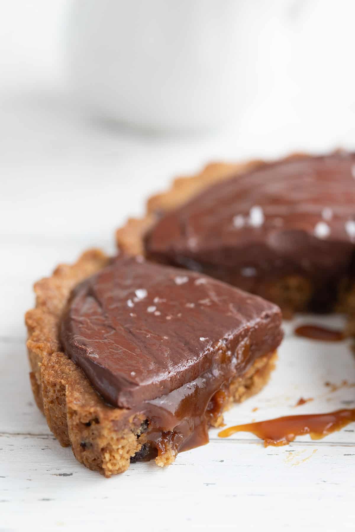 Close up shot of a slice of keto caramel tart with the caramel sauce oozing out.
