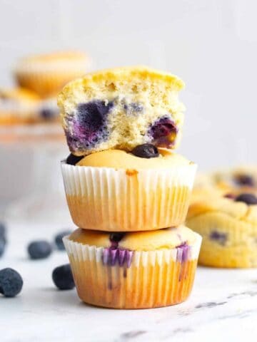 Keto blueberry muffins in a stack with the top one broken open.