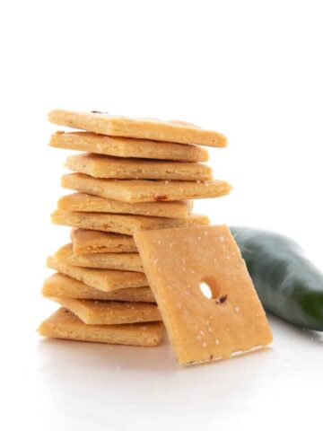 A stack of Keto Cheese Crackers on a white background with a jalapeno.