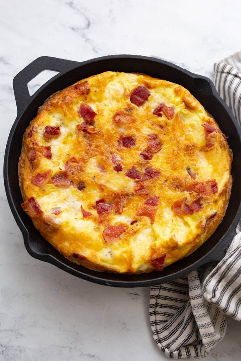 Puffy keto frittata in a cast iron skillet with a striped napkin.