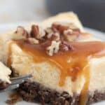 Titled image of a Keto Caramel Cheesecake Bar on a white plate with sugar-free caramel sauce and chopped pecans on top.