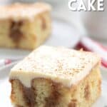 Titled Pinterest image of a slice of Keto Cinnamon Roll Poke Cake on a white plate over a red and white striped napkin.