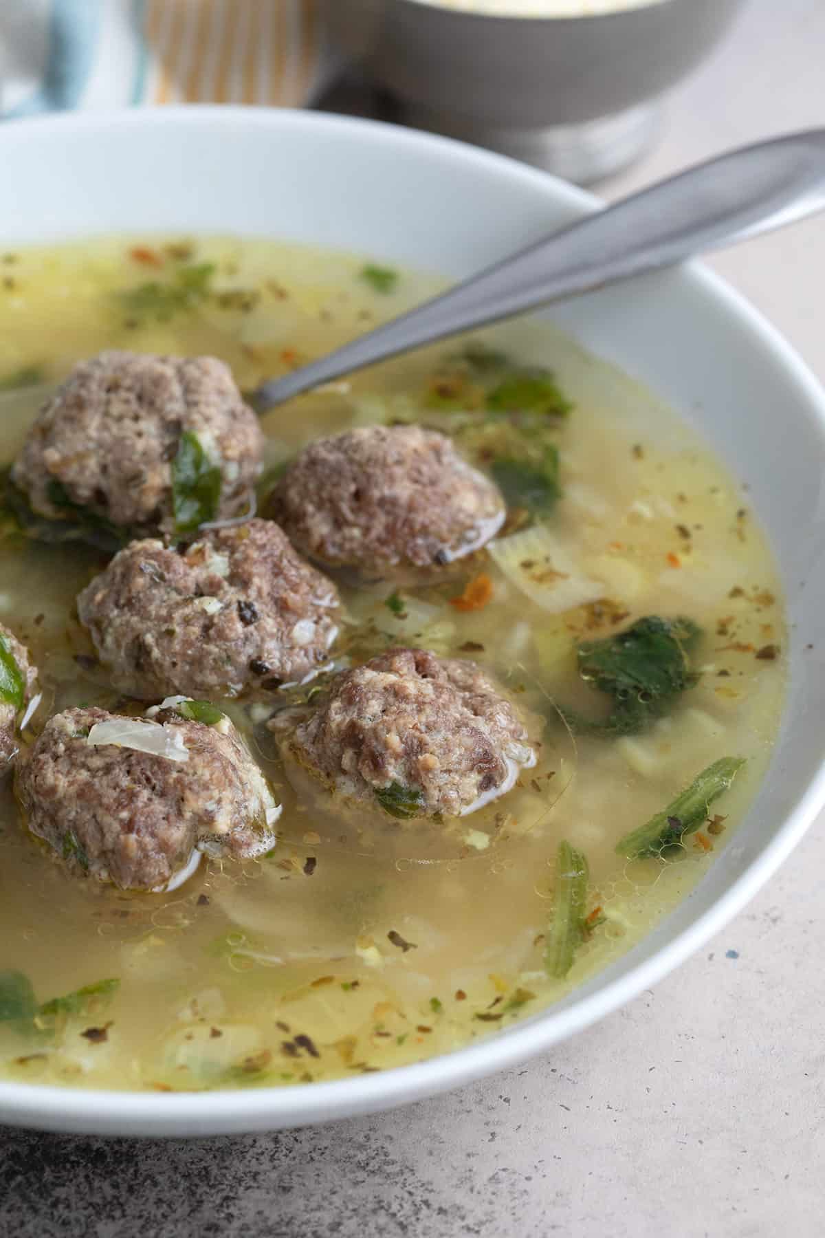 Close up shot of Italian Wedding Soup in a white bowl.