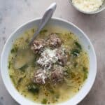 Top down image of a white bowl filled with Italian Wedding Soup.