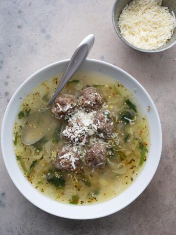 Top down image of a white bowl filled with Italian Wedding Soup.