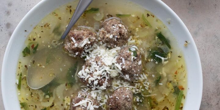 Top down image of a white bowl filled with Italian Wedding Soup.