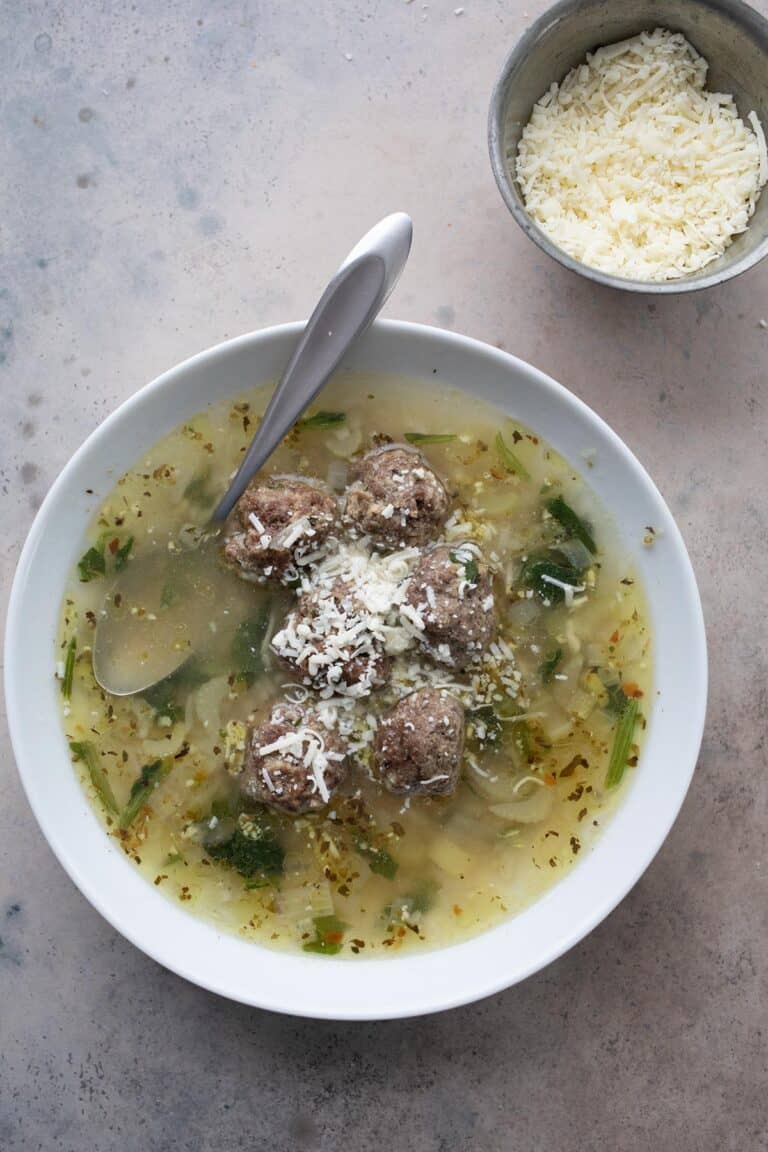 Top down image of a white bowl filled with Italian Wedding Soup.