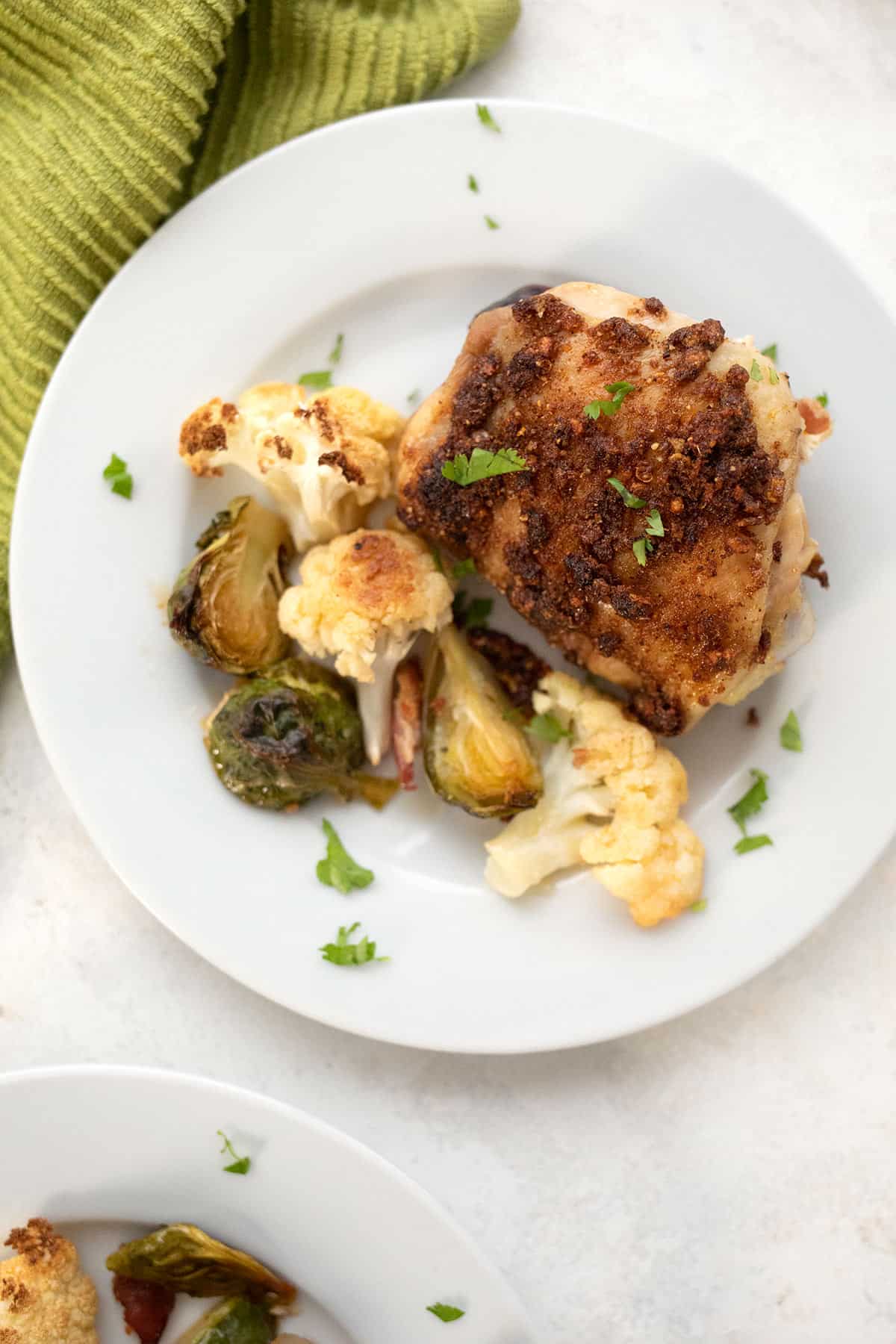 Top down image of a plate with sheet pan chicken and veggies.