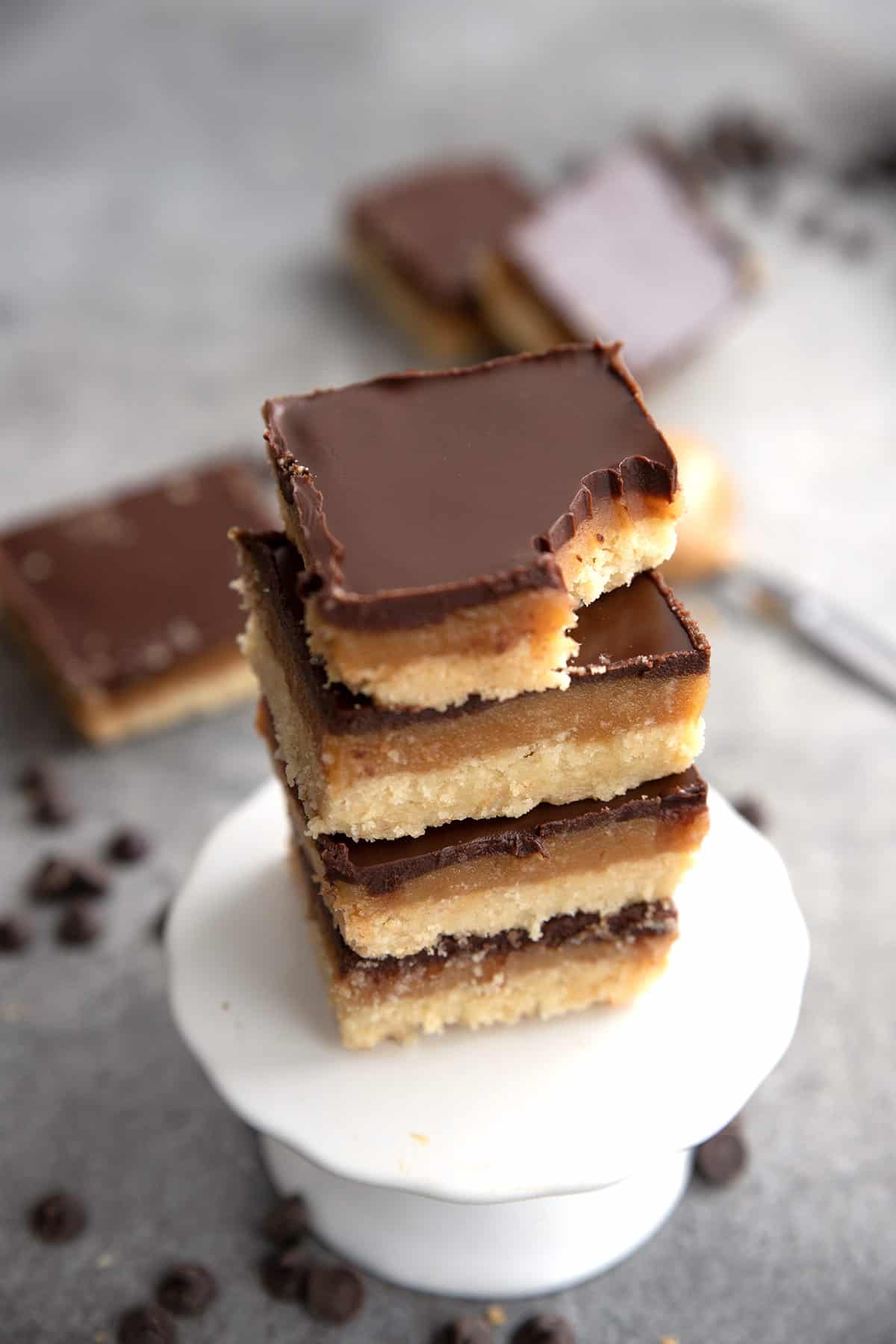 Keto Tagalong Bars in a stack on a white cupcake stand with a bite taken out of the top one.