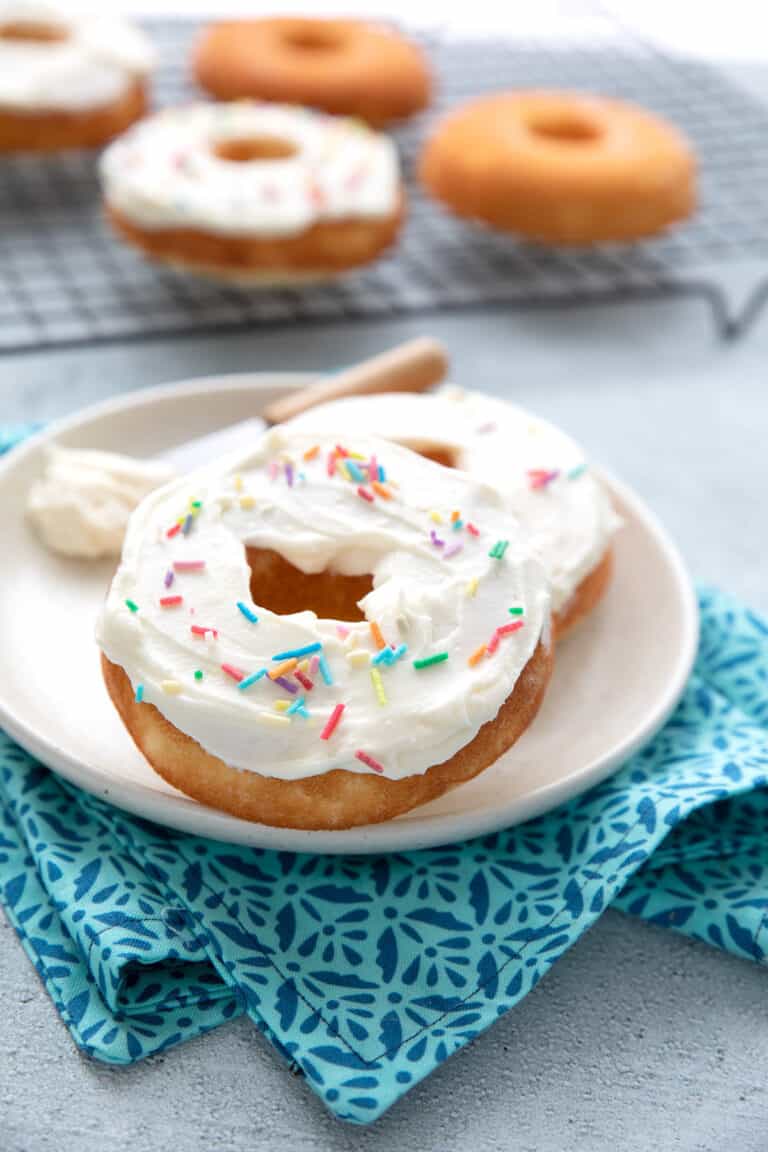 Two keto protein donuts on a white plate over a blue patterned napkin.