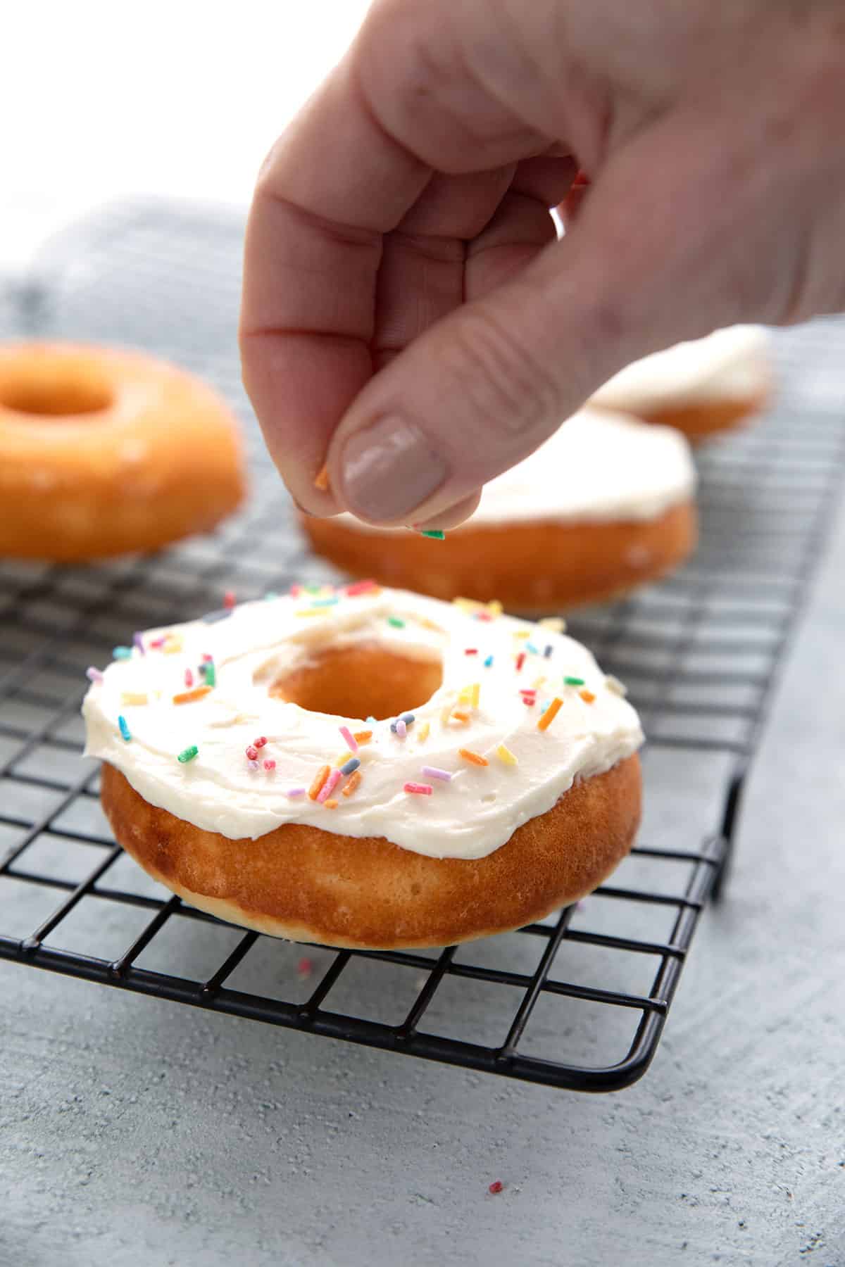 Placing keto sprinkles on a vanilla protein donut.