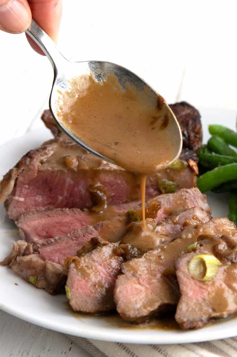 Close up shot of sauce being poured over Steak Diane.