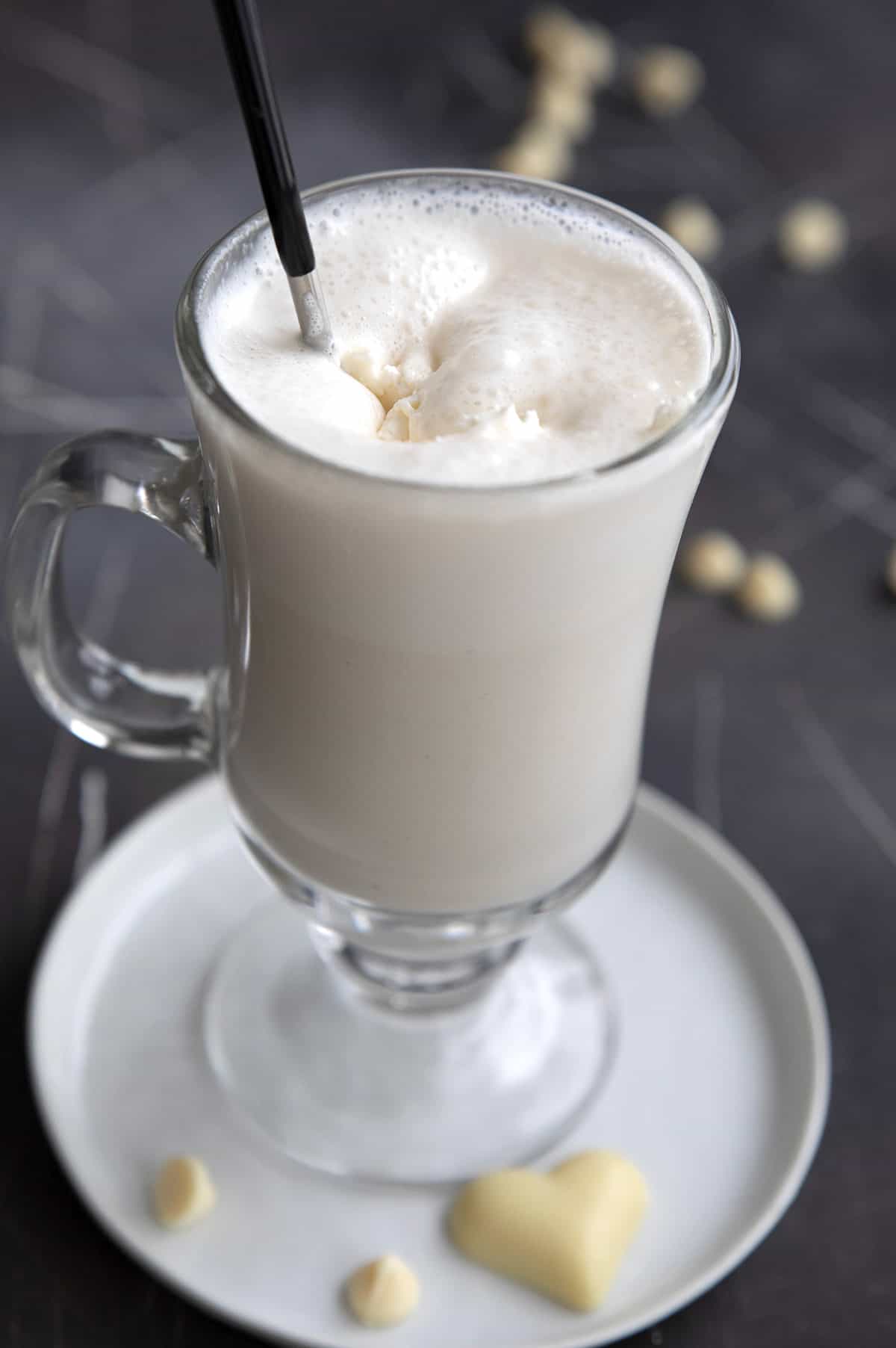 A spoon stirring a mug of keto white hot chocolate.