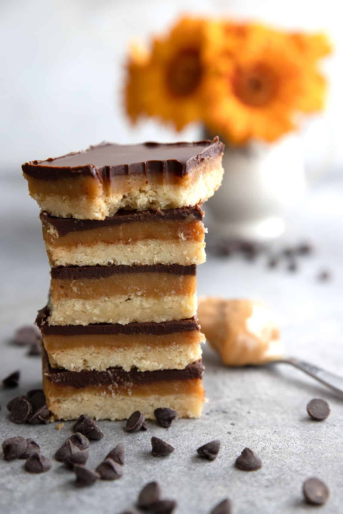 Keto Tagalong Bars in a stack on a grey table with orange flowers in the background.