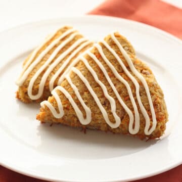 Two keto carrot cake scones on a white plate over an orange napkin.