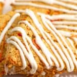 Titled image close up of keto carrot cake scones piled up on a white plate.