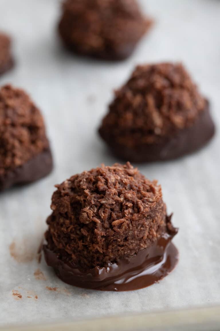 Close up shot of a chocolate dipped keto macaroon on a white tray.