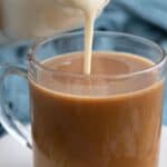 Keto Coffee Creamer being poured from a glass bottle into a cup of coffee.