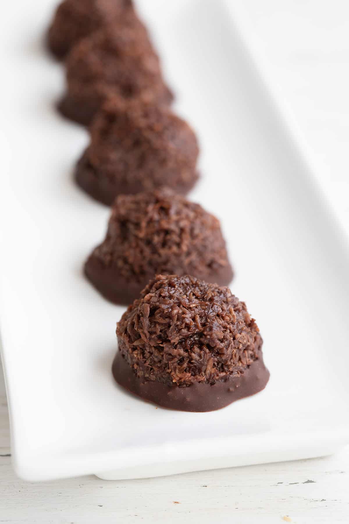 Chocolate keto macaroons lined up on a long white tray.