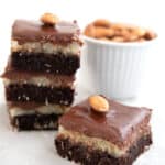 A Keto Almond Joy Brownie on a grey table with a stack of more brownies in behind.