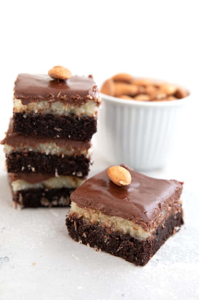 A Keto Almond Joy Brownie on a grey table with a stack of more brownies in behind.