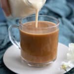 Pouring keto coffee creamer from the bottle into a cup of coffee.