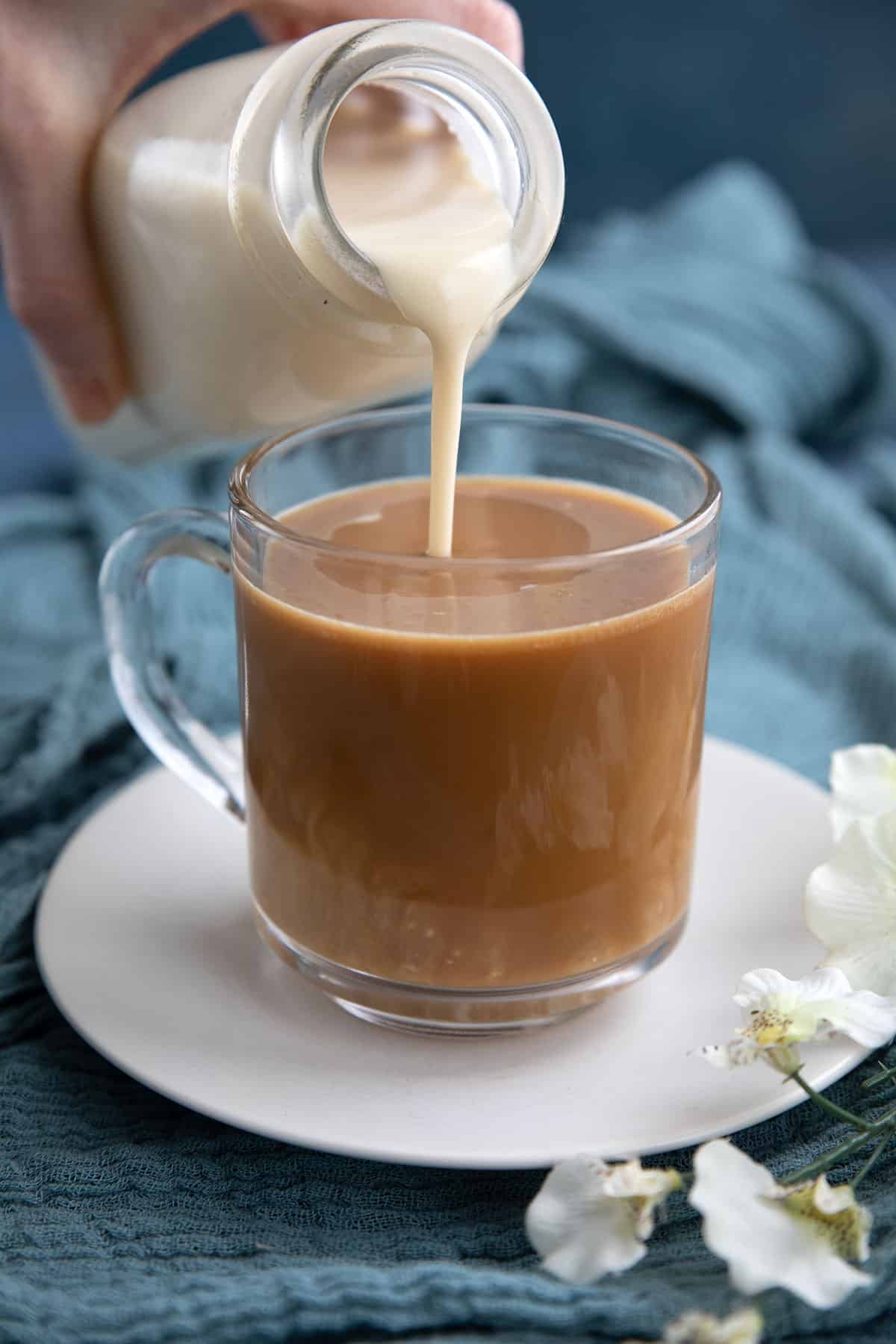 Pouring keto coffee creamer from the bottle into a cup of coffee.