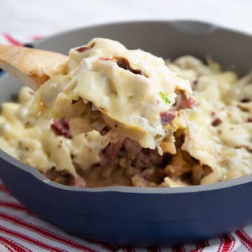 A wooden spoon lifting Reuben Casserole out of the pan.