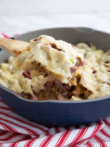 A wooden spoon lifting Reuben Casserole out of the pan.