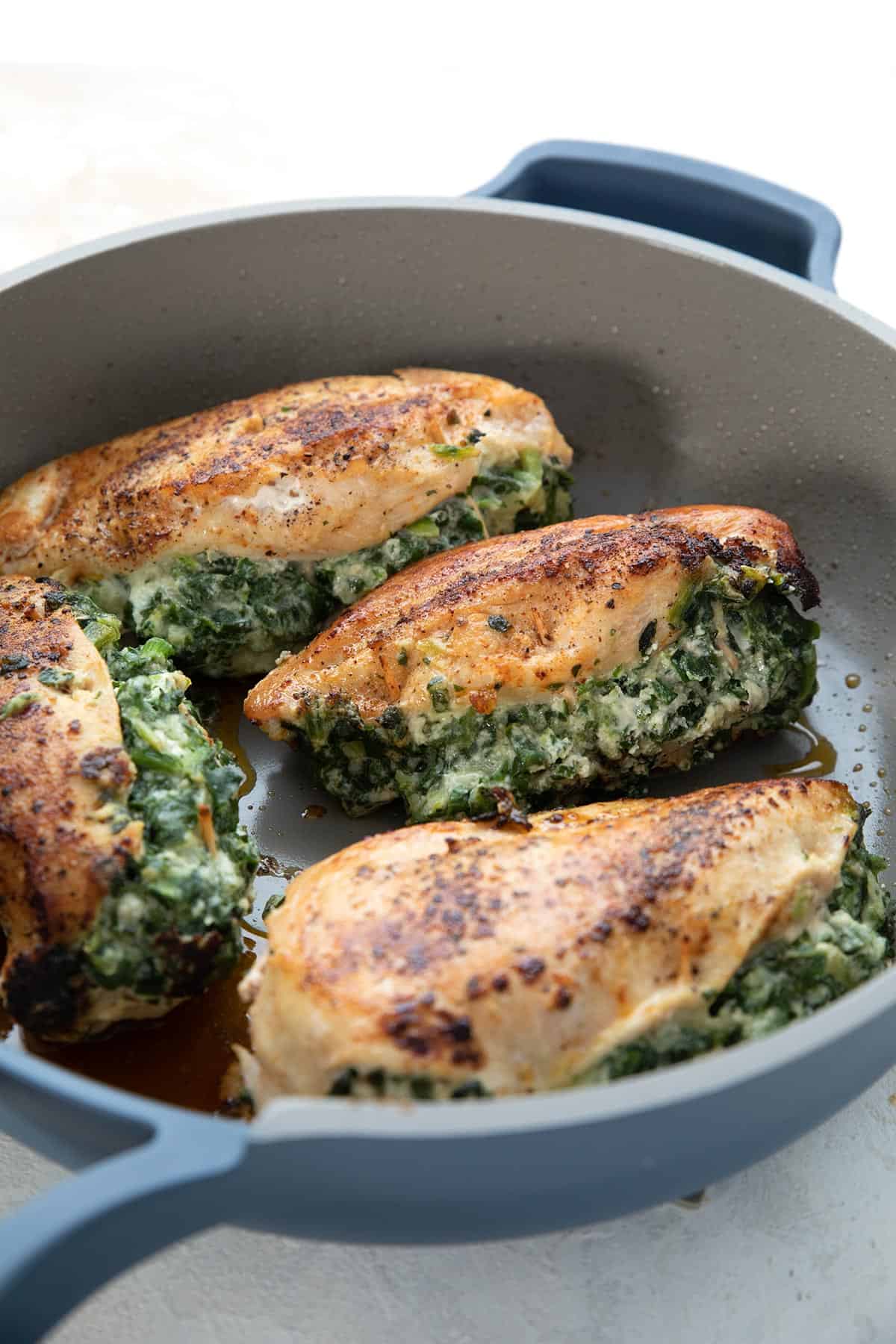 Spinach Stuffed Chicken Breasts in a blue skillet.
