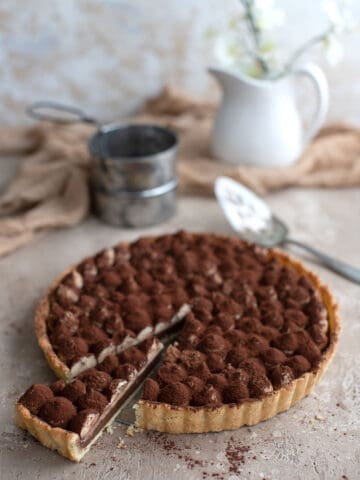 Keto Tiramisu Tart on a brown table with a slice cut out of it.
