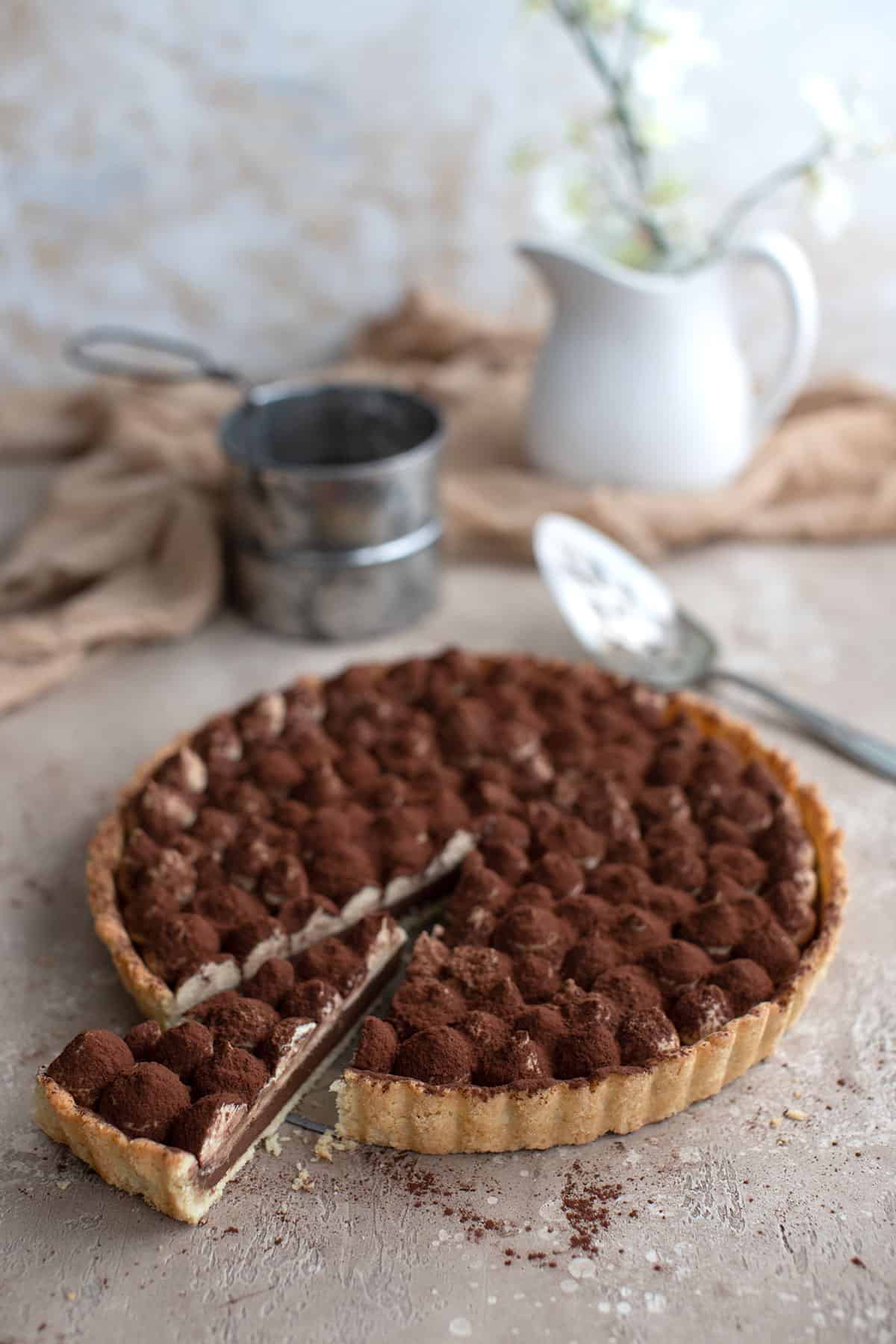 Keto Tiramisu Tart on a brown table with a slice cut out of it.