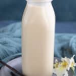 Keto low carb coffee creamer in a glass bottle with vanilla beans in front.