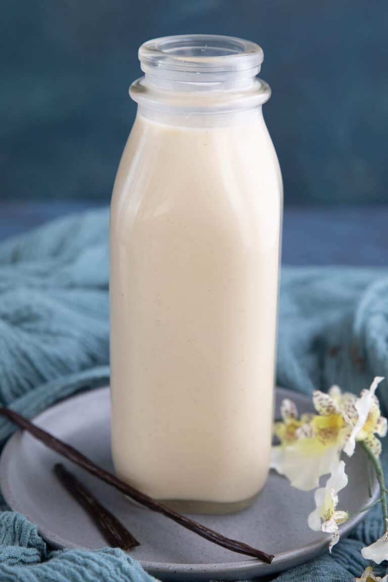 Keto low carb coffee creamer in a glass bottle with vanilla beans in front.