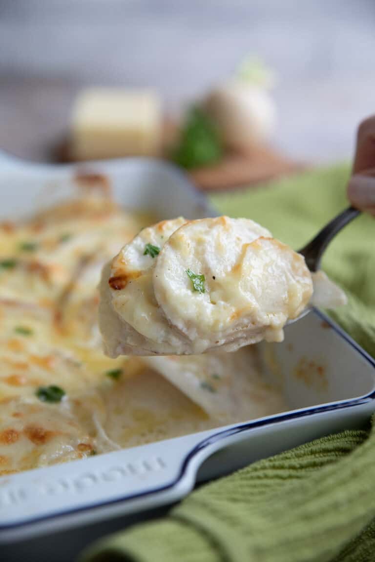 A spoon lifting Turnip au Gratin out of the serving dish.