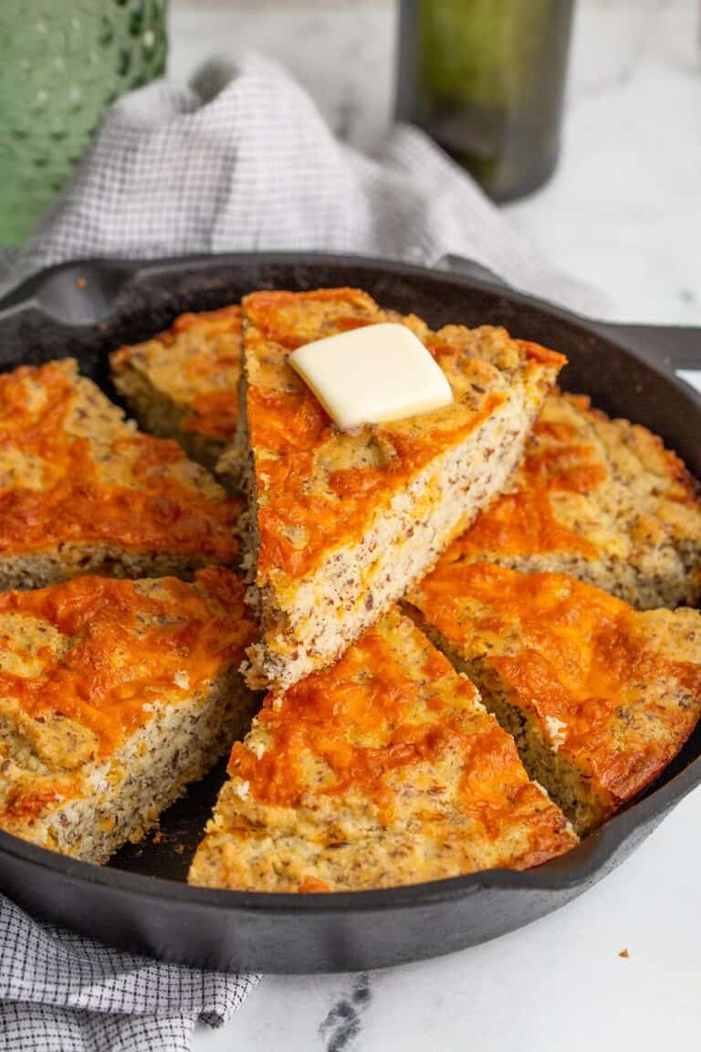 A slice of easy keto cheese bread on top of the remaining slices in a cast iron pan.