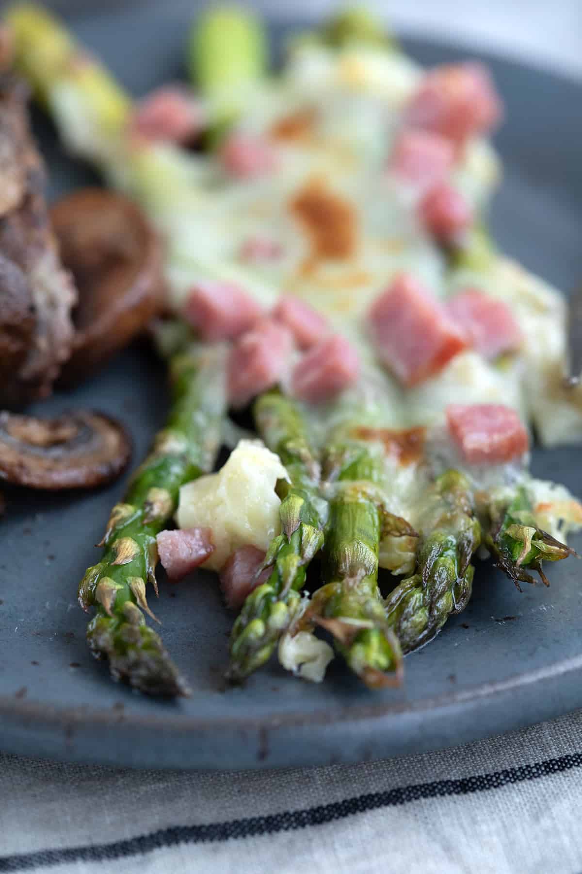Close up shot of keto baked asparagus on a rustic blue plate.