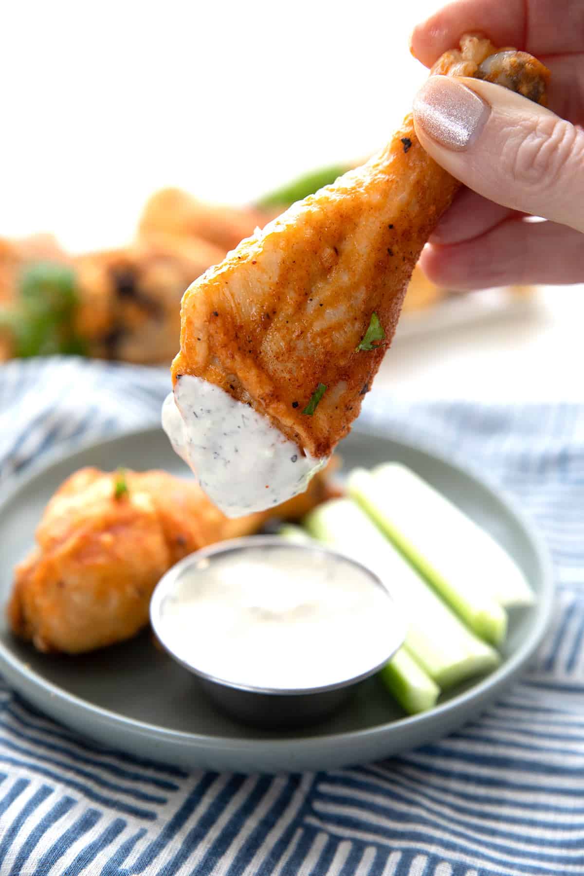 A hand holding up a piece of Keto Buffalo Chicken dipped in ranch dressing.